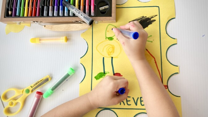 A child drawing on a yellow paper Description automatically generated with low confidence