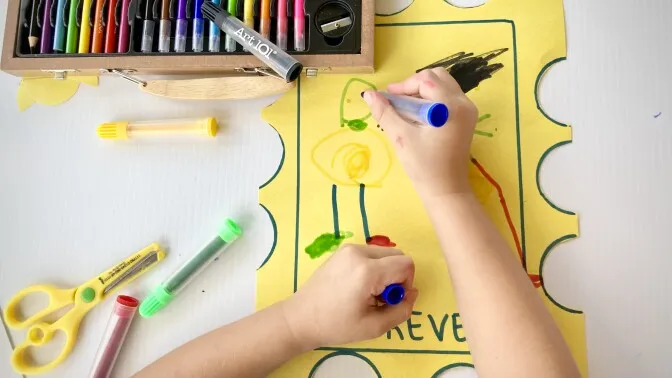 A child drawing on a yellow paper Description automatically generated with low confidence